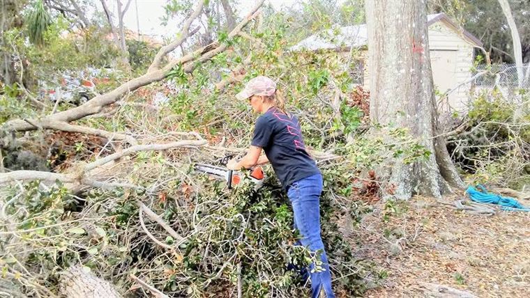 Jenniffer bucking up a downed tree with a chainsaw after a storm.